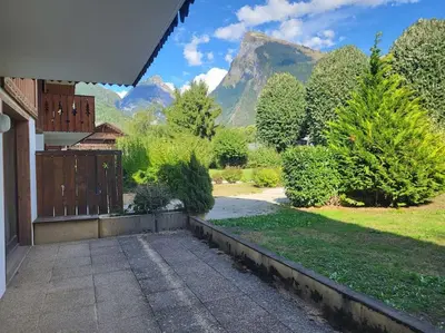 a house with a garden with a mountain in the background at A1/2, 3 bedroom apartment next to the ski lift in Samoëns