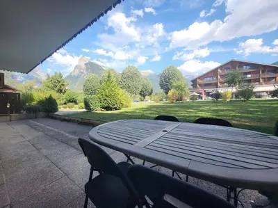 a picnic table with chairs and a view of a mountain at A1/2, 3 bedroom apartment next to the ski lift in Samoëns