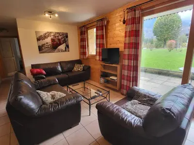 a living room with leather couches and a television at A1/2, 3 bedroom apartment next to the ski lift in Samoëns
