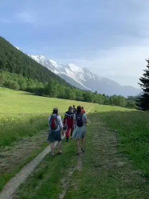 a group of people walking down a dirt road at chalet l'ilet ensoleillé /Sunny Island Chalet in Chamonix-Mont-Blanc