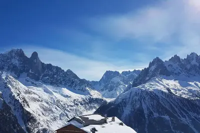 a snow covered mountain range with a house in the foreground at chalet l'ilet ensoleillé /Sunny Island Chalet in Chamonix-Mont-Blanc