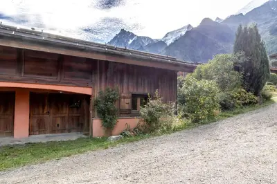 a building with a barn with mountains in the background at Les Cristalliers - Cozy family chalet - Close to the village in Les Houches