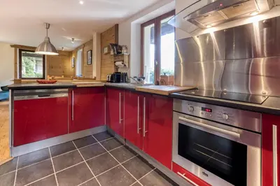 a kitchen with red cabinets and stainless steel appliances at AO HOUSE - PRAKKA Base Camp in Les Houches
