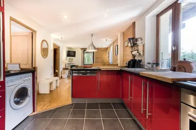 a kitchen with red cabinets and a washer and dryer at AO HOUSE - PRAKKA Base Camp in Les Houches