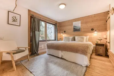 a bedroom with a bed and a chair and a window at AO HOUSE - PRAKKA Base Camp in Les Houches