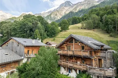 a group of wooden buildings with mountains in the background at AO HOUSE - PRAKKA Base Camp in Les Houches