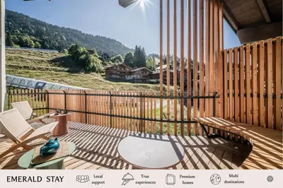 a wooden deck with a table and chairs on it at Apartment Tourmalet Carrôz d'Arâches - BY EMERALD STAY in Les Carroz d'Araches