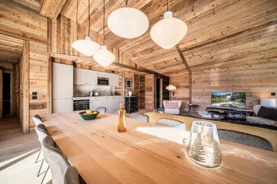 a dining room and kitchen with a wooden table and lights at Apartment Tourmalet Carrôz d'Arâches - BY EMERALD STAY in Les Carroz d'Araches