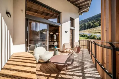 a deck with chairs and a table on a house at Apartment Tourmalet Carrôz d'Arâches - BY EMERALD STAY in Les Carroz d'Araches