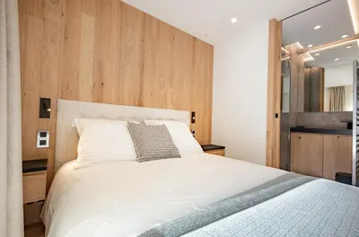 a bedroom with a white bed and wooden walls at L'Ecrin Blanc Megève in Megève