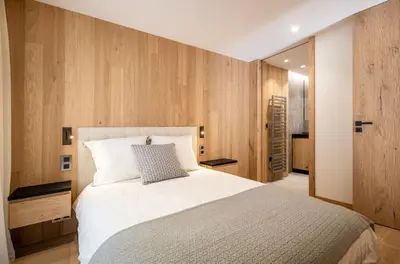 a bedroom with a white bed and wooden walls at L'Ecrin Blanc Megève in Megève