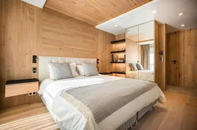 a bedroom with a large bed and wooden walls at L'Ecrin Blanc Megève in Megève