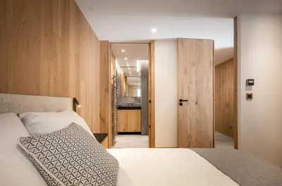 a bedroom with a bed and a door to a bathroom at L'Ecrin Blanc Megève in Megève