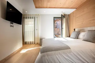 a bedroom with a large bed with a flat screen tv at L'Ecrin Blanc Megève in Megève