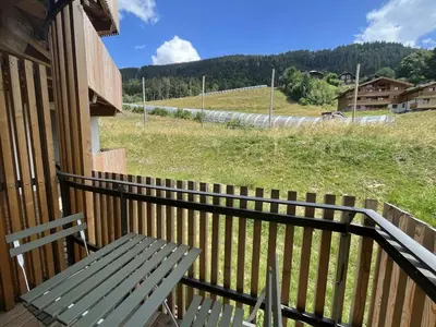 a bench sitting on a porch with a view of a field at Superbe appart 3P au pied des pistes, parking couvert, terrasse, WiFi - Les Carroz - FR-1-572-288 in Arâches-la-Frasse