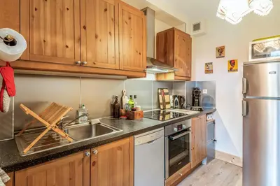 a kitchen with wooden cabinets and a stainless steel refrigerator at Appartement Yodel - Welkeys in Saint-Gervais-les-Bains