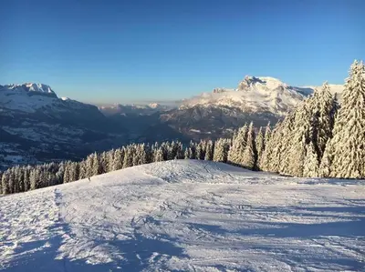 a snow covered hill with trees and mountains in the background at Chalet à Saint-Gervais-les-Bains, 8 personnes, 4 chambres in Saint-Gervais-les-Bains
