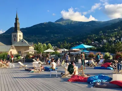 a group of people sitting on a patio with a church at Chalet à Saint-Gervais-les-Bains, 8 personnes, 4 chambres in Saint-Gervais-les-Bains
