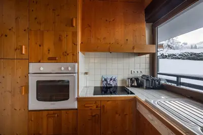 a kitchen with wooden cabinets and a microwave at Flat - Le Whivern A stone's throw from the village centre in Megève