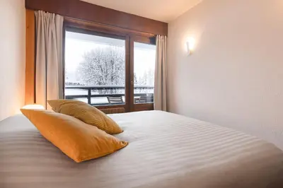 a bedroom with a bed with two pillows and a window at Flat - Le Whivern A stone's throw from the village centre in Megève