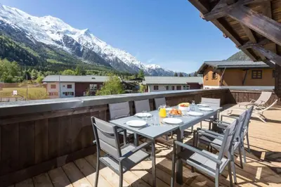a table on a balcony with a view of a mountain at Grand Paradis- Modern 3 bedroom apartment with spectacular views in Chamonix-Mont-Blanc