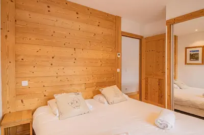 a bedroom with two beds and a wooden wall at Grand Paradis- Modern 3 bedroom apartment with spectacular views in Chamonix-Mont-Blanc