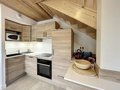 a kitchen with wooden cabinets and a staircase in a room at Bel appartement 4 pièces près du village, parking inclus - FR-1-560-115 in Combloux