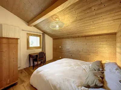 a bedroom with a bed and a wooden wall at Bel appartement 4 pièces près du village, parking inclus - FR-1-560-115 in Combloux
