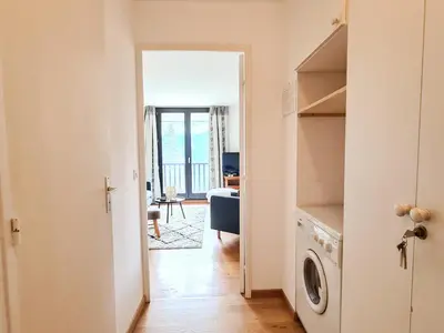a hallway with a door open to a living room with a washing machine at Appartement lumineux · Centre station · 6 pers · Balcon · WI-FI - FR-1-425-205 in Arâches-la-Frasse