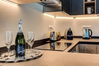 a bottle of wine on a counter with two wine glasses at Apartment Alpes V - Alpes Travel - Central Chamonix - Sleeps 5 in Chamonix-Mont-Blanc