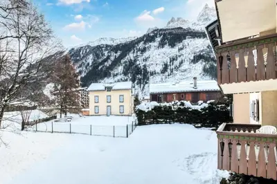 a house in the snow with mountains in the background at Résidence La Ginabelle - maeva Home - Appartement 4 Pièces 8 Personnes - Sélection MAE-7444 in Chamonix-Mont-Blanc