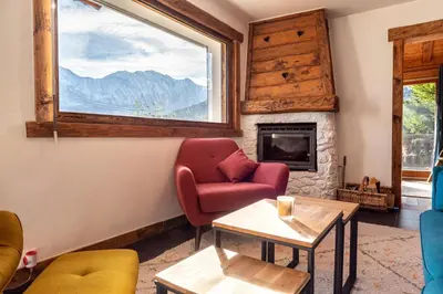 a living room with a fireplace and a red chair at Le Relief - Maison avec magnifique vue montagne aux Bettex in Saint-Gervais-les-Bains