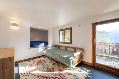 a bedroom with a bed and a window and a rug at Le Relief - Maison avec magnifique vue montagne aux Bettex in Saint-Gervais-les-Bains