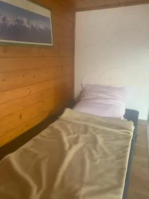 a small bedroom with a bed in a wooden room at LES TOURISTES in Combloux