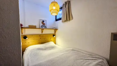 a small bedroom with a bed with a white blanket at Résidence Verseau - Appartement lumineux et spacieux · Centre station · avec cabine et Balcon MAE-8894 in Magland