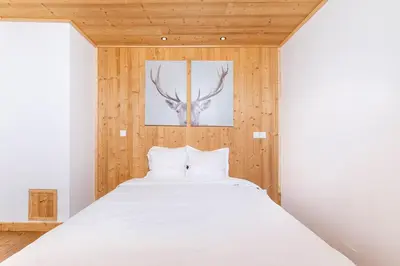 a bedroom with a white bed with a deer head on the wall at Résidence Les Arcades du Mont-Blanc in Megève