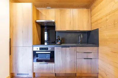 a kitchen with wooden cabinets and a stove at Résidence Les Arcades du Mont-Blanc in Megève