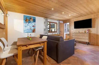 a living room with a dining room table and a television at Résidence Les Arcades du Mont-Blanc in Megève