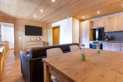 a dining room with a wooden table and a kitchen at Résidence Les Arcades du Mont-Blanc in Megève