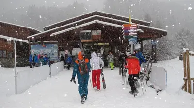 a group of people walking in the snow in front of a building at Charmant mobilhome à 2 pas remontés ski Samoëns in Samoëns