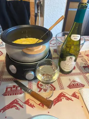 a pot of food and a bottle of wine on a table at Arve et Giffre Samoens 1600 in Samoëns