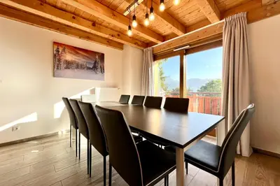 a dining room with a table and chairs and a large window at Flocon du Medonnet in Combloux