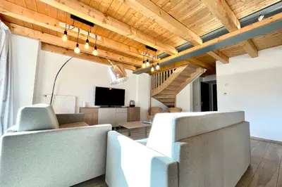 a living room with white furniture and wooden ceilings at Flocon du Medonnet in Combloux