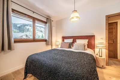 a bedroom with a large bed and a window at Apartment Centaurea Megève - BY EMERALD STAY in Megève