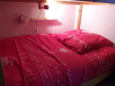 a bed with a red comforter in a bedroom at Studio 4 couchages 