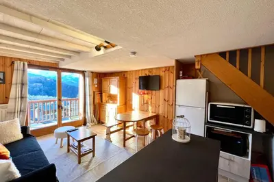 a kitchen and living room with a table and a refrigerator at Le Doux Sapin in Saint-Gervais-les-Bains