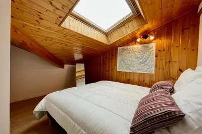 a bedroom with a large white bed with a skylight at Le Doux Sapin in Saint-Gervais-les-Bains