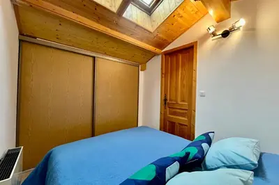 a bedroom with a blue bed with a wooden ceiling at Le Doux Sapin in Saint-Gervais-les-Bains