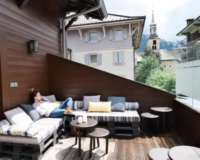 a cup of coffee sitting on a ledge with mountains at Chalet hôtel le Whymper in Chamonix-Mont-Blanc