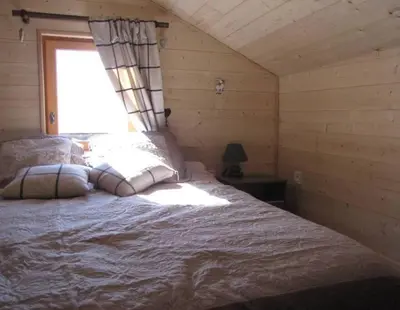 a bed in a wooden room with a window at Sublime maison 15 personnes in Saint-Gervais-les-Bains